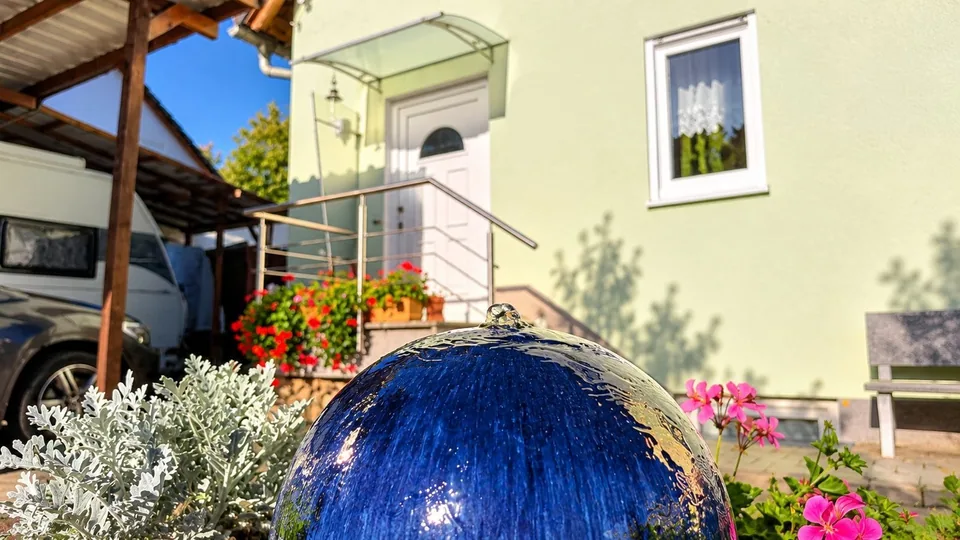 Glänzende blaue Brunnenkugel im Vorgarten.png